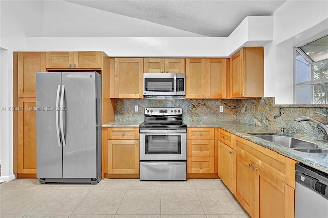 kitchen with light stone countertops, appliances with stainless steel finishes, decorative backsplash, and a sink