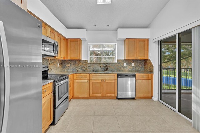 kitchen featuring sink, stainless steel appliances, light stone countertops, and lofted ceiling