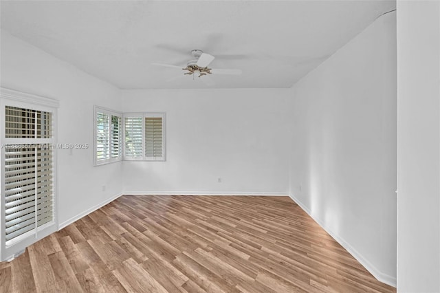 spare room featuring a ceiling fan, light wood-style flooring, and baseboards