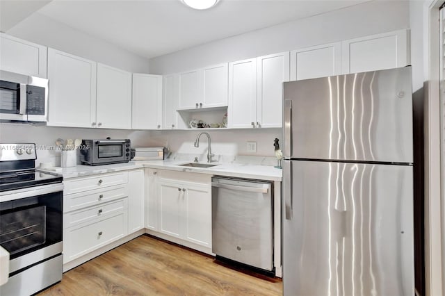 kitchen with white cabinetry, stainless steel appliances, sink, and light wood-type flooring