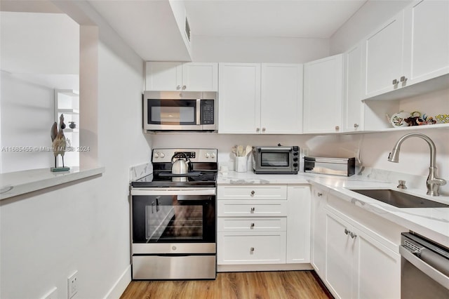 kitchen featuring white cabinetry, stainless steel appliances, sink, and light wood-type flooring