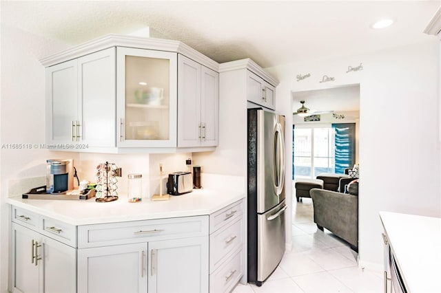 kitchen with a textured ceiling, light tile patterned floors, and stainless steel fridge