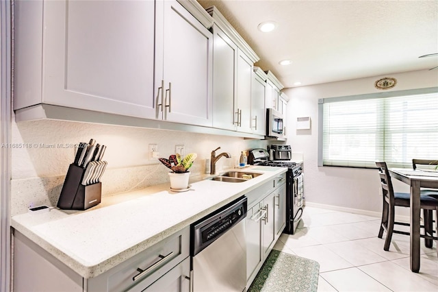 kitchen featuring light stone counters, stainless steel appliances, white cabinetry, light tile patterned floors, and sink