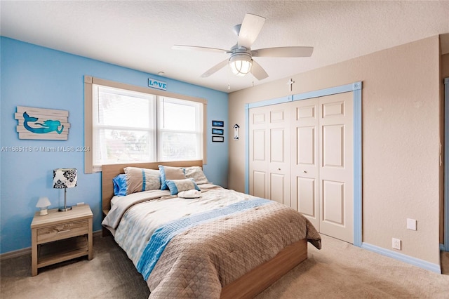 bedroom featuring a closet, a textured ceiling, light carpet, and ceiling fan