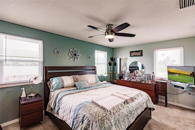 bedroom featuring ceiling fan, multiple windows, a textured ceiling, and carpet floors