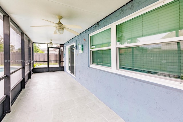 unfurnished sunroom with ceiling fan