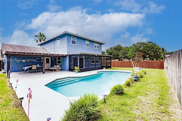 view of swimming pool featuring a lawn, a patio, and a sunroom