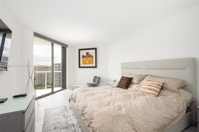 bedroom featuring expansive windows, access to outside, multiple windows, and light hardwood / wood-style flooring