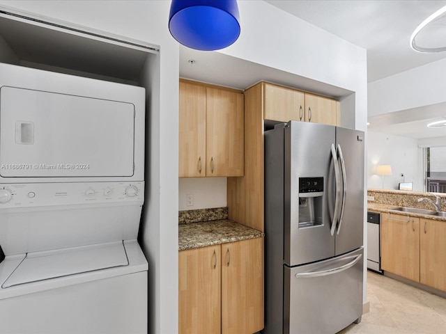 laundry area with stacked washer and dryer and sink