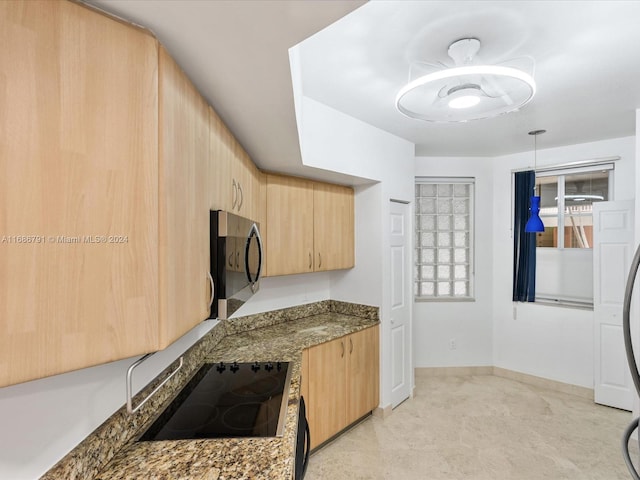 kitchen featuring hanging light fixtures, light brown cabinetry, black range, and dark stone countertops