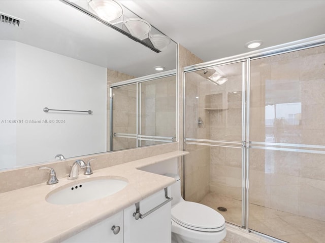 bathroom with a shower with shower door, vanity, and toilet