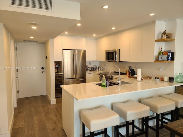 kitchen featuring a breakfast bar area, white cabinets, stainless steel appliances, and dark hardwood / wood-style flooring