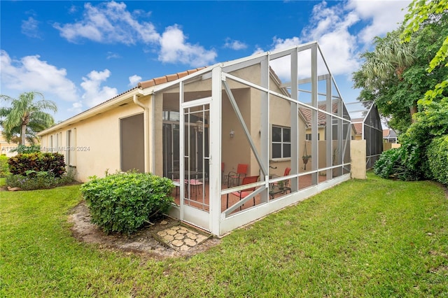 rear view of house with glass enclosure and a yard