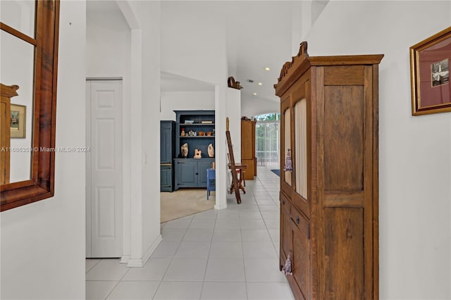 hallway featuring light tile patterned floors and lofted ceiling