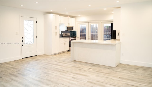 kitchen with white cabinets, kitchen peninsula, stainless steel appliances, and light hardwood / wood-style floors