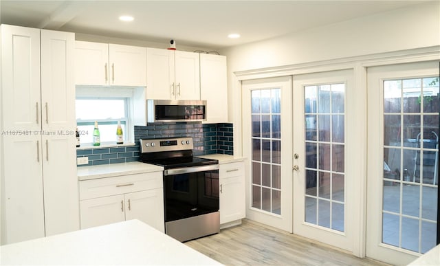 kitchen with backsplash, white cabinetry, stainless steel appliances, and light hardwood / wood-style floors