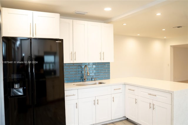 kitchen with sink, white cabinets, kitchen peninsula, and black fridge with ice dispenser