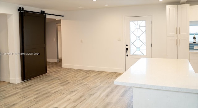 foyer entrance featuring light hardwood / wood-style floors, a barn door, and plenty of natural light