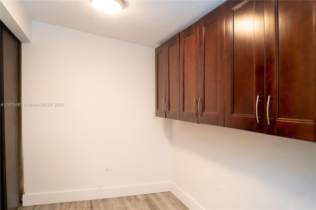 laundry room featuring a textured ceiling and light wood-type flooring