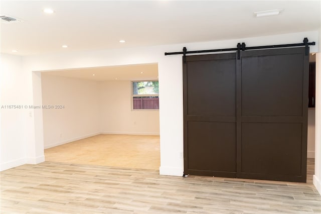 unfurnished room featuring a barn door and light wood-type flooring