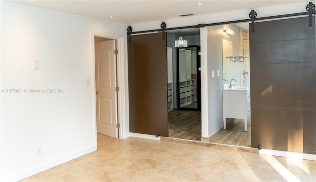 unfurnished room with light hardwood / wood-style floors, sink, and a barn door