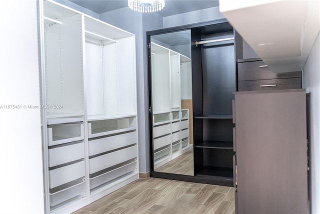 spacious closet with a chandelier and light wood-type flooring