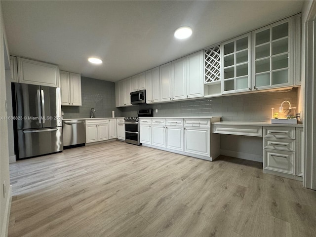 kitchen featuring decorative backsplash, stainless steel appliances, sink, white cabinetry, and light hardwood / wood-style floors