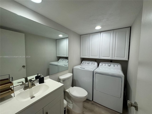 bathroom featuring a textured ceiling, washing machine and clothes dryer, toilet, vanity, and hardwood / wood-style flooring