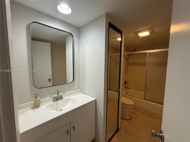 full bathroom featuring vanity, toilet, tile patterned floors, and bath / shower combo with glass door