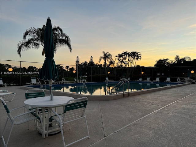 pool at dusk with a patio area