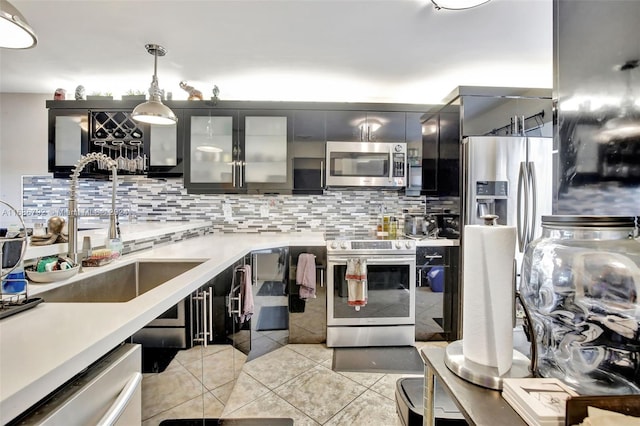 kitchen featuring tasteful backsplash, stainless steel appliances, sink, light tile patterned floors, and decorative light fixtures