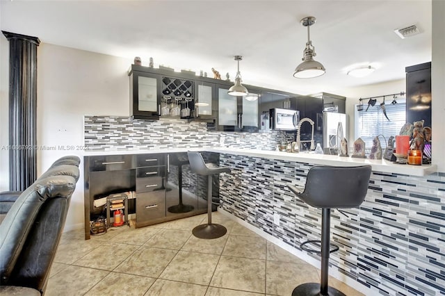 interior space featuring backsplash, pendant lighting, light tile patterned floors, and stainless steel appliances