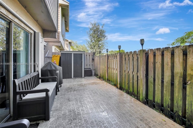 view of patio / terrace featuring a storage shed and a grill