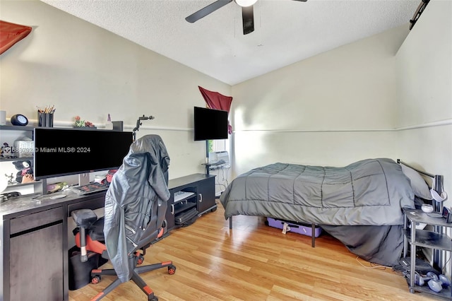 bedroom featuring vaulted ceiling, ceiling fan, light hardwood / wood-style flooring, and a textured ceiling