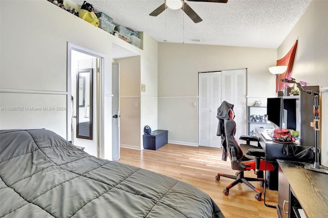 bedroom with ceiling fan, light wood-type flooring, lofted ceiling, and a textured ceiling