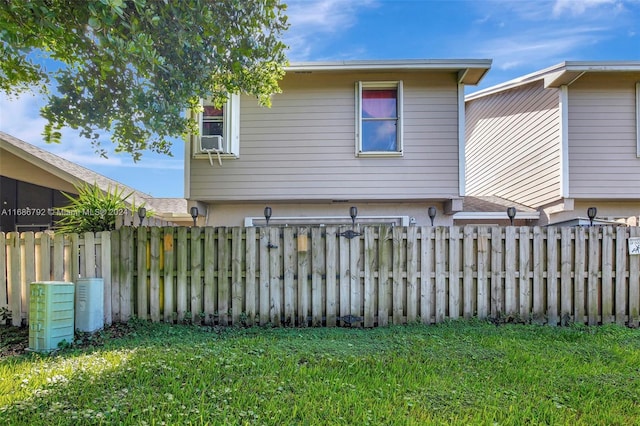 rear view of property with cooling unit and a yard