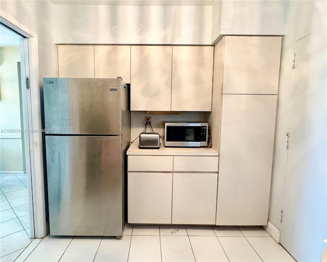 kitchen featuring light tile patterned floors, white cabinets, and appliances with stainless steel finishes