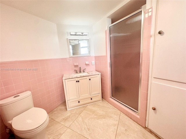 bathroom featuring a shower with shower door, tile walls, vanity, toilet, and tile patterned floors