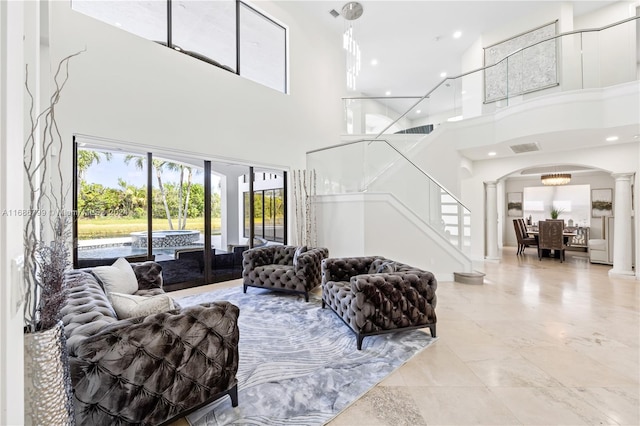 living room featuring decorative columns and a towering ceiling