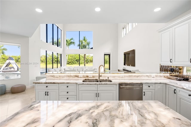 kitchen with white cabinetry, sink, light stone counters, and dishwasher