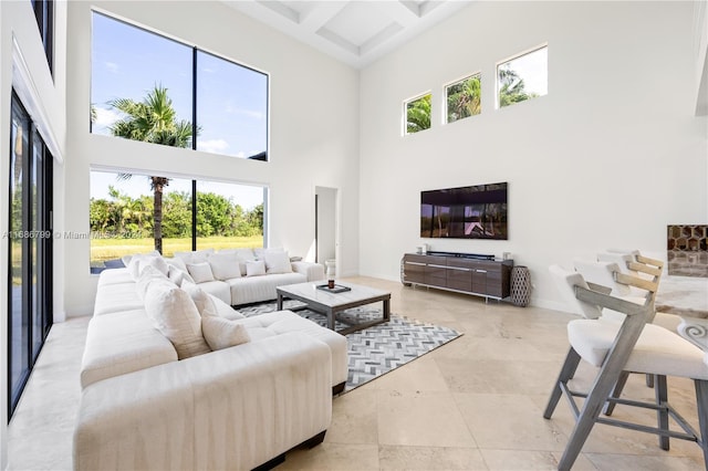 tiled living room featuring a towering ceiling, a wealth of natural light, beam ceiling, and coffered ceiling