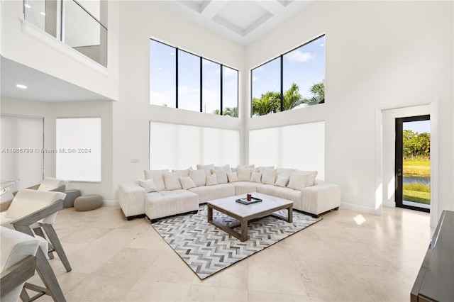 living room featuring a towering ceiling, a healthy amount of sunlight, and light tile patterned floors