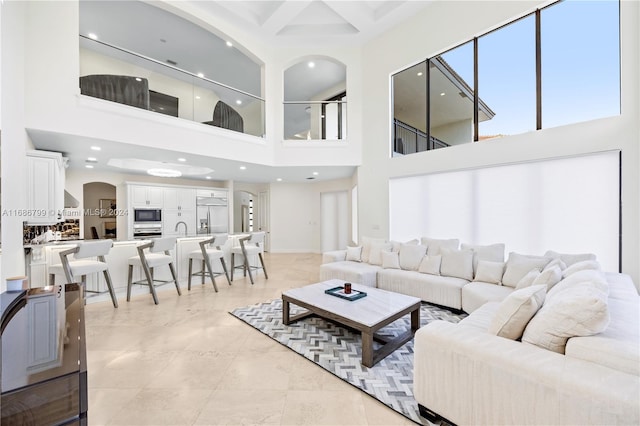 tiled living room with a high ceiling, beamed ceiling, sink, and coffered ceiling