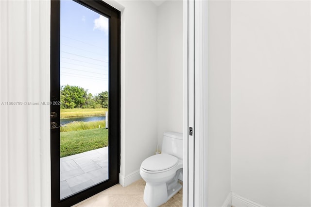 bathroom featuring a water view, tile patterned floors, and toilet