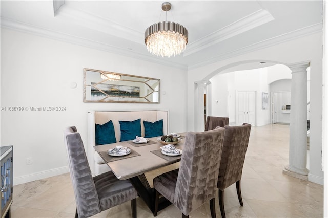 dining space with crown molding, a raised ceiling, decorative columns, and an inviting chandelier