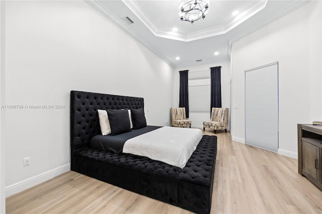 bedroom with light wood-type flooring, a raised ceiling, crown molding, and a notable chandelier