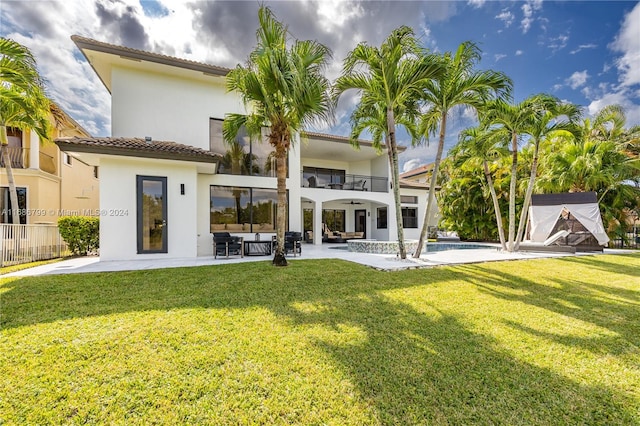 rear view of property featuring an outdoor hangout area, a patio area, a balcony, and a yard