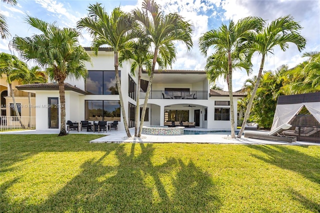 rear view of property featuring outdoor lounge area, a lawn, a patio, and a balcony