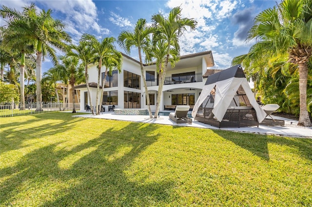 rear view of property featuring a patio, a yard, an outdoor living space, and a balcony