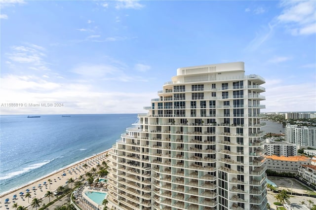 view of building exterior featuring a water view and a beach view